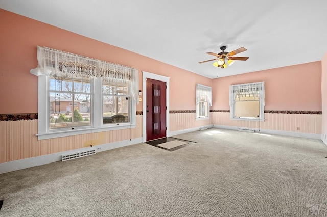 interior space with ceiling fan, visible vents, and a wainscoted wall