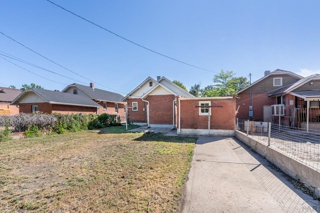 ranch-style house with a front yard, fence, and brick siding