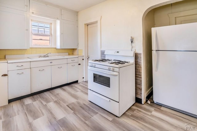 kitchen with light wood-style flooring, white appliances, a sink, white cabinetry, and light countertops