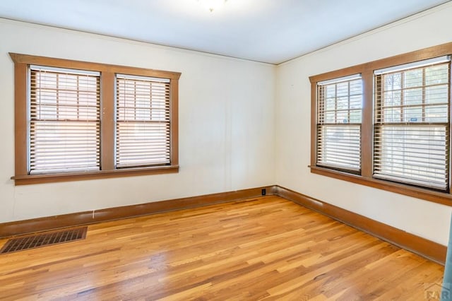 unfurnished room with baseboards, crown molding, visible vents, and light wood-style floors