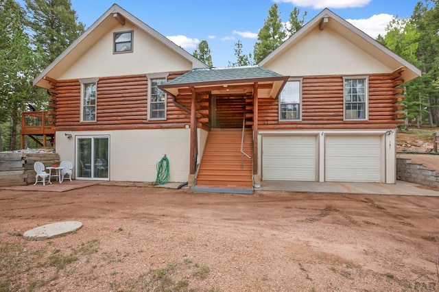 131 Kestrel Ct, Divide, CO 80814 - back of property with log exterior, stairs, a garage, dirt driveway, and roof with shingles