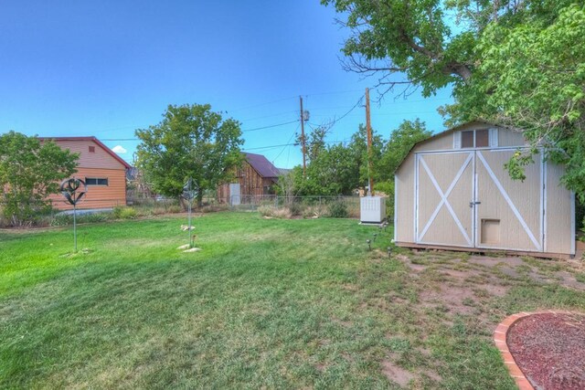 view of yard featuring an outdoor structure, fence, and a storage shed