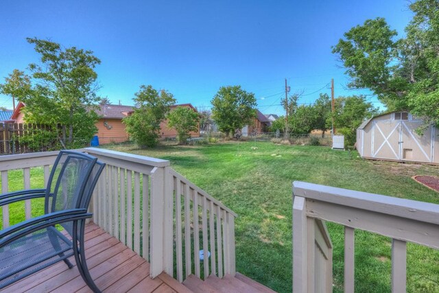 wooden deck with a fenced backyard, a storage unit, an outdoor structure, and a yard