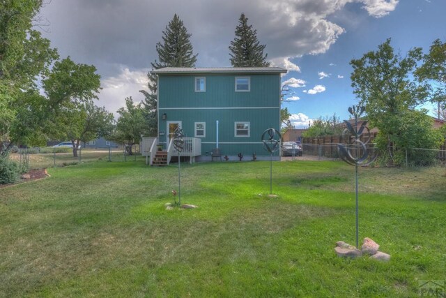 rear view of house featuring fence and a yard