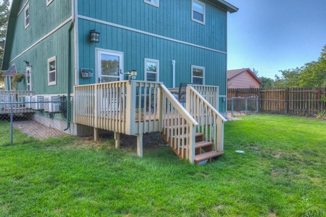 rear view of property with a fenced backyard, a lawn, and a deck