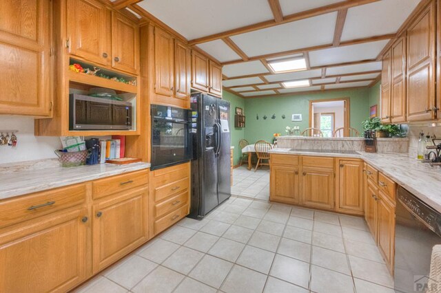 kitchen featuring light stone counters, brown cabinets, light tile patterned flooring, a peninsula, and black appliances