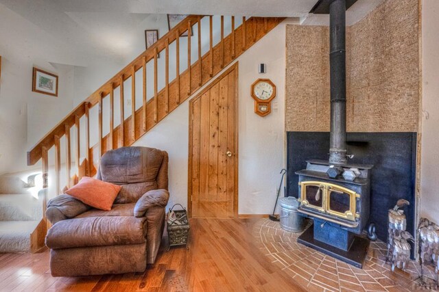 living room with stairway, wood finished floors, a wood stove, and baseboards