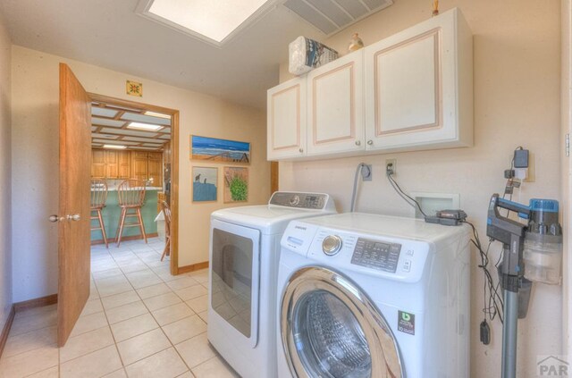 clothes washing area featuring washer and clothes dryer, light tile patterned floors, visible vents, cabinet space, and baseboards