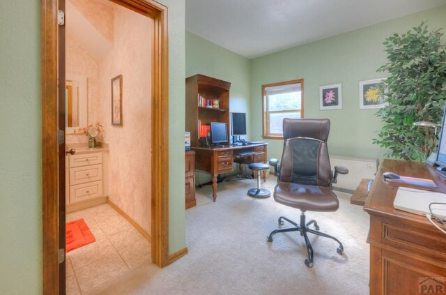 office featuring light tile patterned floors, baseboards, and light colored carpet