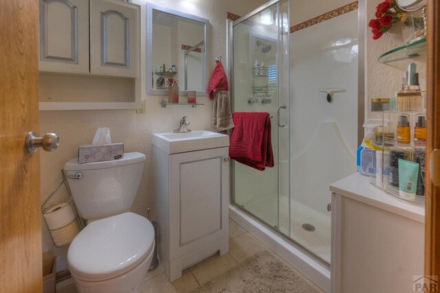 bathroom featuring a stall shower, tile patterned flooring, vanity, and toilet