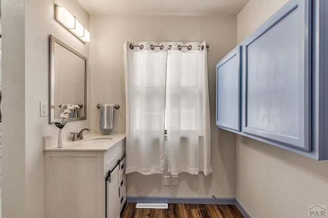 bathroom featuring visible vents, vanity, baseboards, and wood finished floors