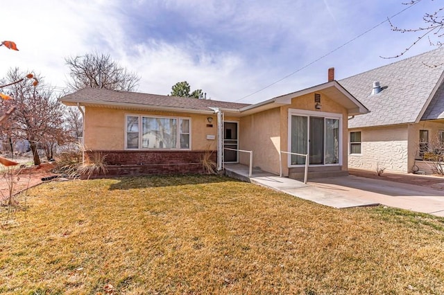 view of front facade with a front yard, a patio area, and stucco siding