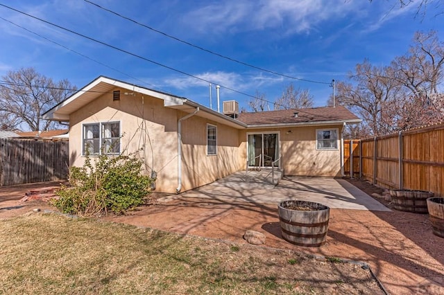 rear view of property with stucco siding, a patio, central AC, and a fenced backyard