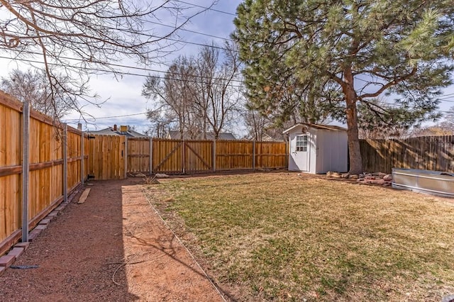 view of yard featuring an outdoor structure, a gate, a fenced backyard, and a shed