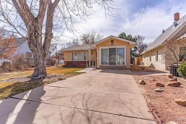 view of front of property with stucco siding, concrete driveway, and fence