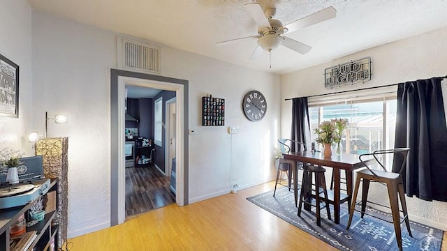 dining room featuring ceiling fan, visible vents, baseboards, and wood finished floors