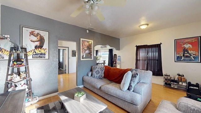 living room with visible vents, baseboards, wood finished floors, a textured wall, and a ceiling fan