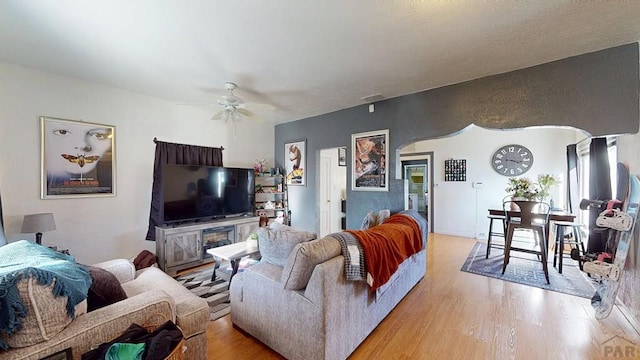 living room featuring visible vents, arched walkways, wood finished floors, and a ceiling fan