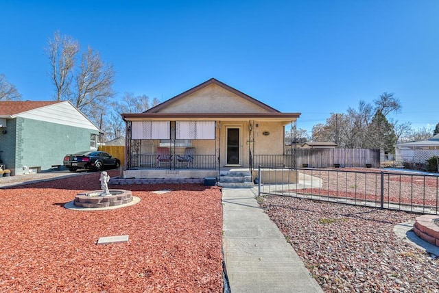 bungalow-style house featuring fence, a porch, and stucco siding