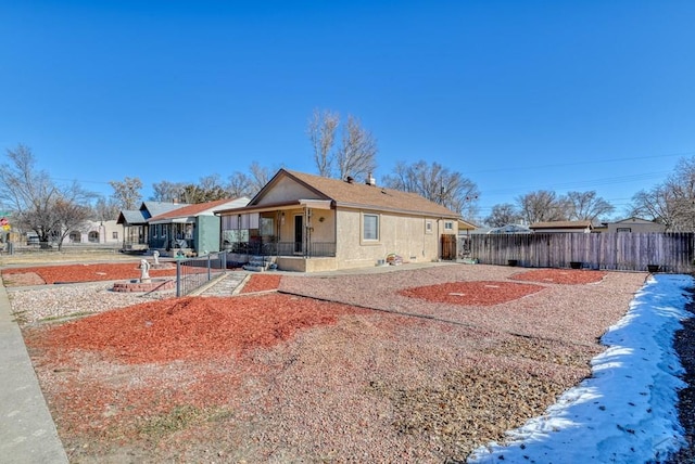 view of front of house featuring a porch, fence private yard, and stucco siding