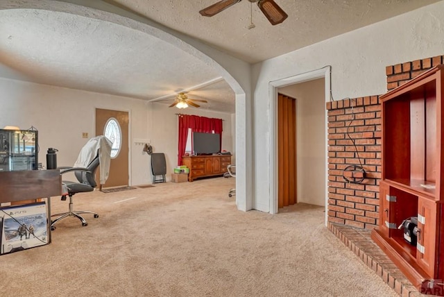 carpeted office featuring a textured ceiling, ceiling fan, arched walkways, and a textured wall