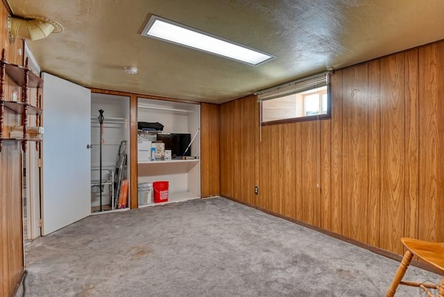 basement with a textured ceiling, light colored carpet, and wooden walls