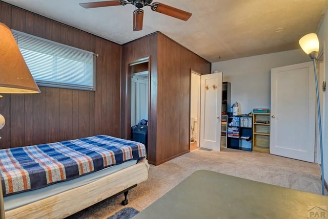 bedroom featuring light carpet, wood walls, and ceiling fan