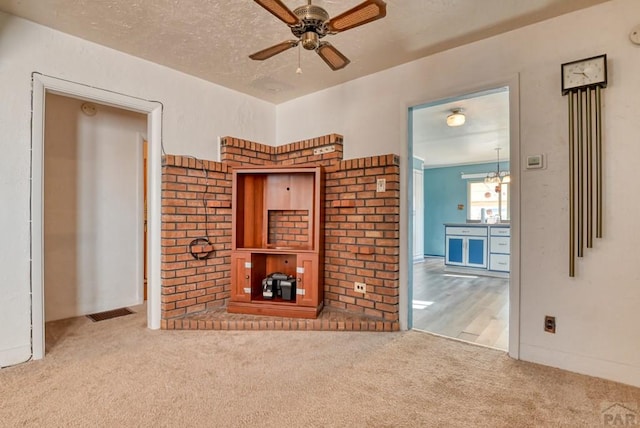 unfurnished living room with visible vents, a ceiling fan, and light colored carpet