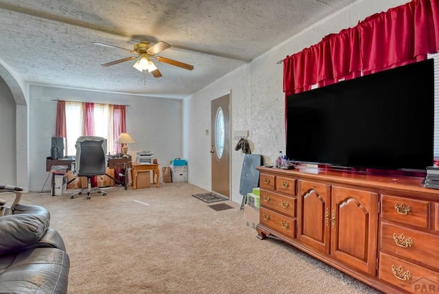 office area with a ceiling fan, arched walkways, a textured ceiling, and light colored carpet