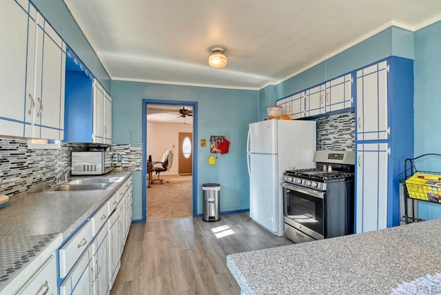 kitchen with a sink, white cabinets, light wood-type flooring, decorative backsplash, and gas stove