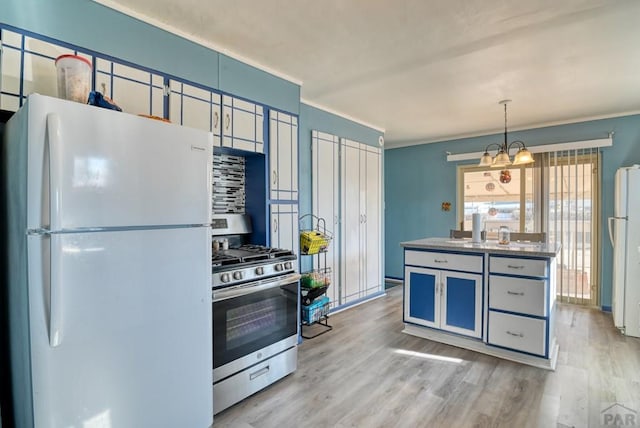 kitchen with stainless steel gas range oven, freestanding refrigerator, hanging light fixtures, light wood-type flooring, and a chandelier