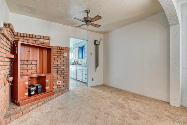 unfurnished living room featuring a ceiling fan, light colored carpet, and a textured ceiling