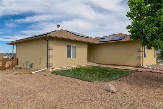 1121 N Calico Rock Ln, Pueblo West, CO 81007 - rear view of house with roof mounted solar panels, stucco siding, and a shingled roof