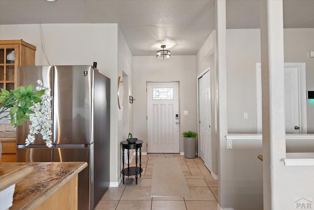 1121 N Calico Rock Ln, Pueblo West, CO 81007 - kitchen featuring freestanding refrigerator, light tile patterned flooring, baseboards, and stone countertops