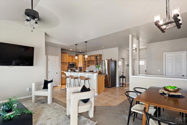 1121 N Calico Rock Ln, Pueblo West, CO 81007 - dining room featuring light tile patterned flooring, vaulted ceiling, a ceiling fan, a chandelier, and baseboards