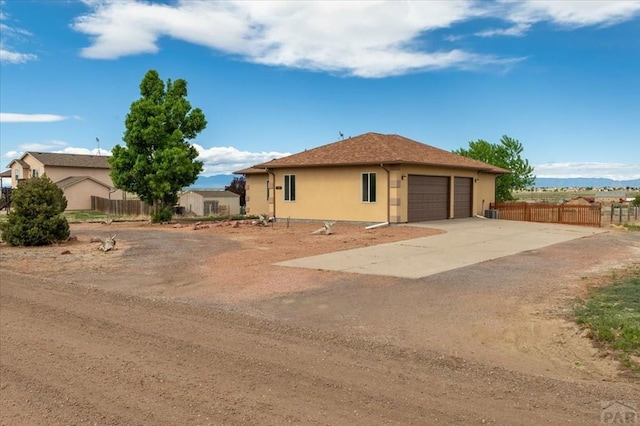 1121 N Calico Rock Ln, Pueblo West, CO 81007 - back of house with stucco siding, dirt driveway, and an attached garage