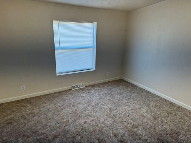 carpeted spare room featuring visible vents and baseboards