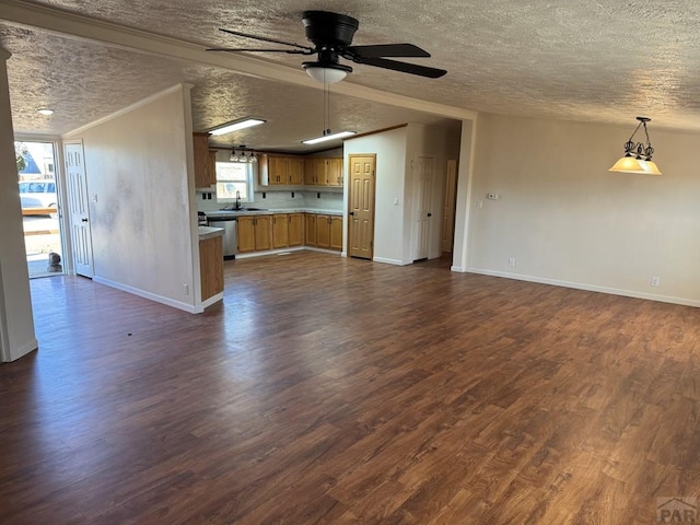 unfurnished living room featuring ceiling fan, a textured ceiling, a sink, ornamental molding, and dark wood-style floors