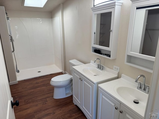 bathroom featuring a shower stall, two vanities, a sink, and wood finished floors