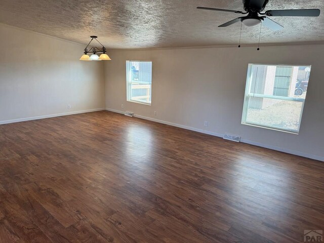 unfurnished room featuring a textured ceiling, ornamental molding, dark wood finished floors, and visible vents