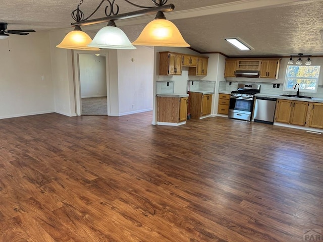 kitchen featuring appliances with stainless steel finishes, brown cabinets, decorative light fixtures, light countertops, and a sink