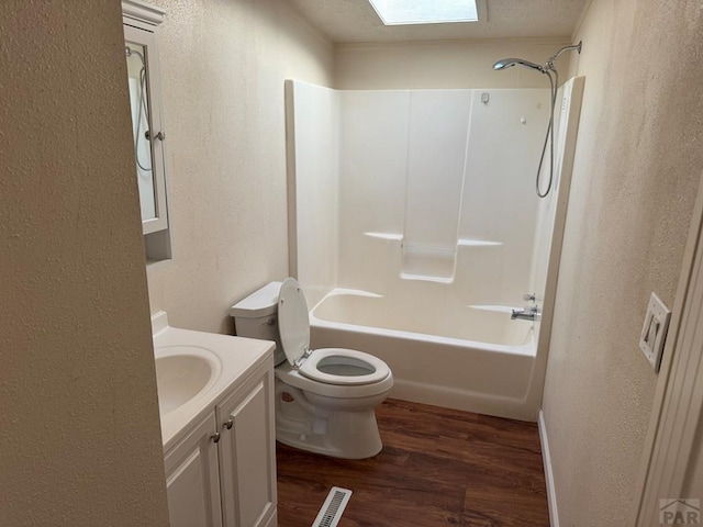 bathroom featuring toilet, wood finished floors, visible vents, vanity, and washtub / shower combination