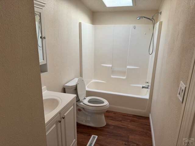 213 Center, Ordway, CO 81063 - bathroom featuring toilet, wood finished floors, visible vents, vanity, and washtub / shower combination