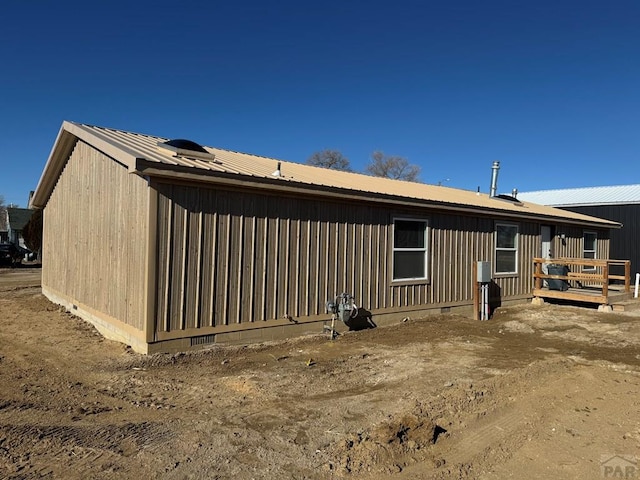 back of house with crawl space and metal roof