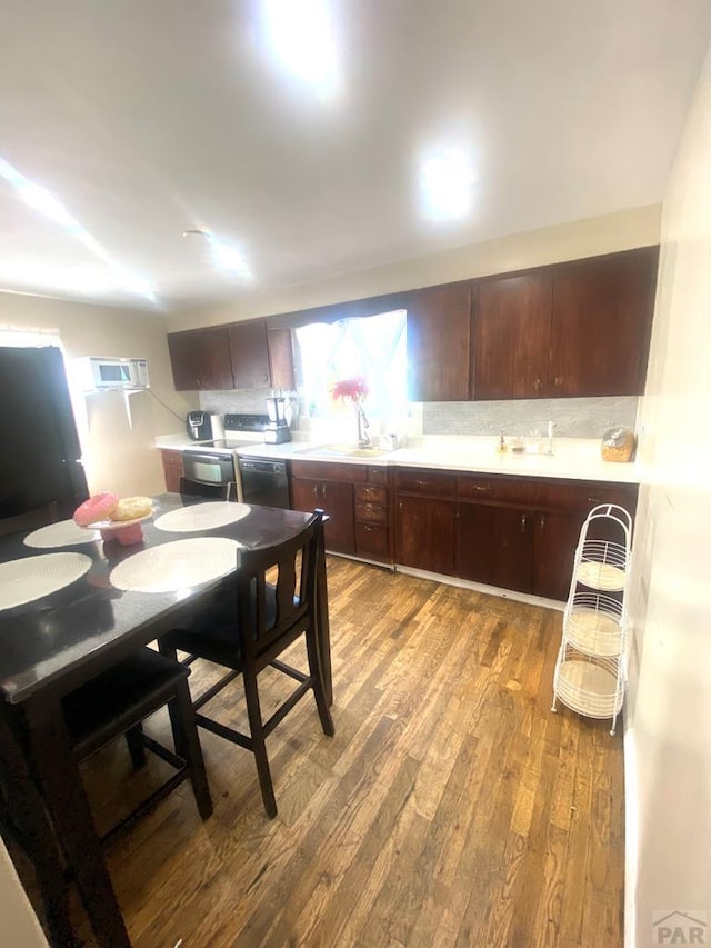 kitchen with decorative backsplash, a sink, dark brown cabinets, wood finished floors, and dishwasher