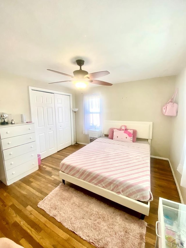 bedroom with a closet, ceiling fan, baseboards, and wood finished floors