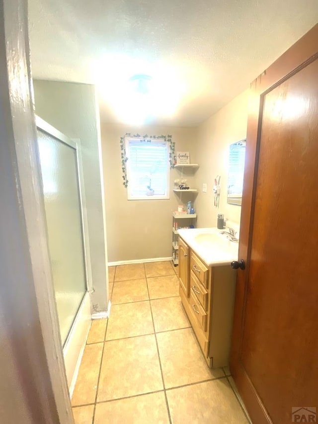 bathroom featuring a textured ceiling, tile patterned flooring, vanity, baseboards, and a shower stall