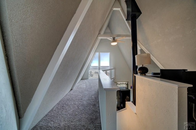 hallway with an upstairs landing, lofted ceiling, and carpet floors