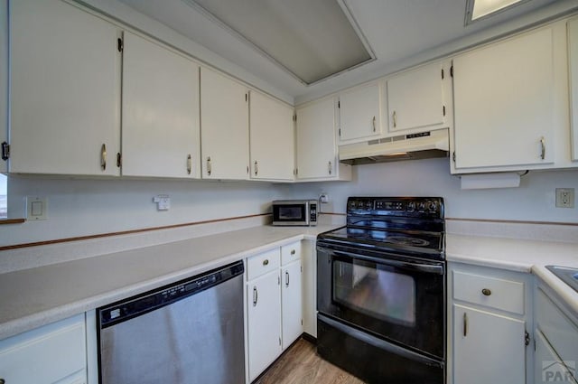 kitchen with under cabinet range hood, wood finished floors, light countertops, and appliances with stainless steel finishes