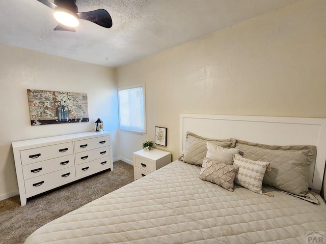 bedroom featuring a textured ceiling, baseboards, dark colored carpet, and a ceiling fan